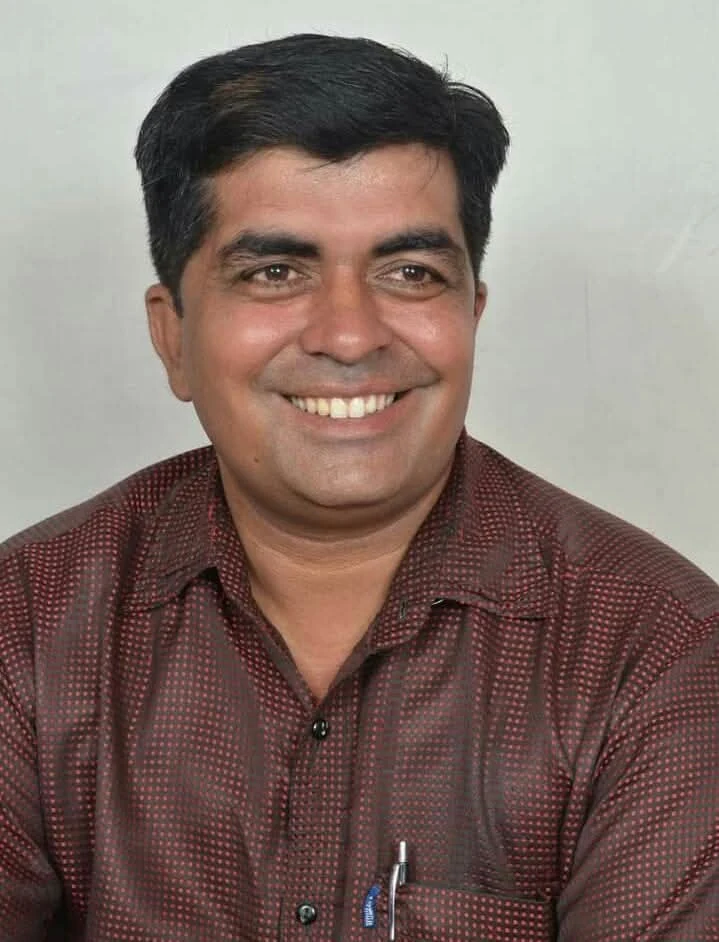 Dr. Avadhesh Kaushik smiling warmly in a scholar bust portrait