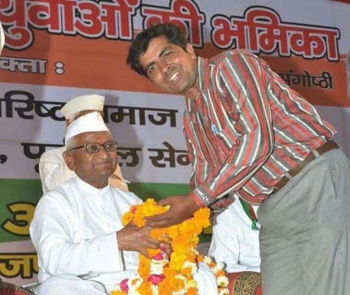 Dr. Avadhesh Kaushik offering flower garland to a senior dignitary on stage